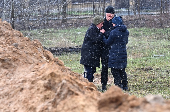 Ukrainians reacting to the sight of a mass grave left after Russian executions of Ukraine civilians at Bucha.