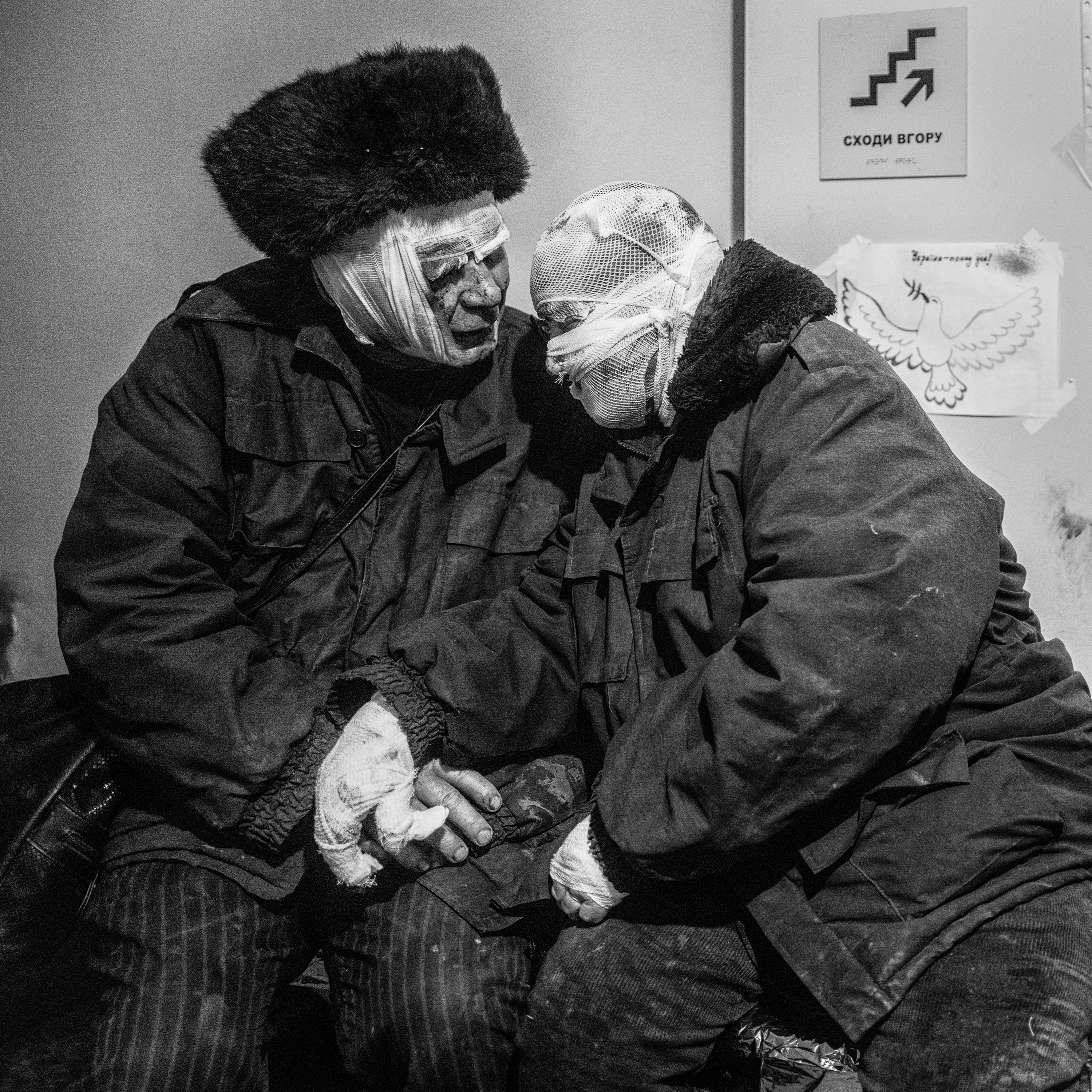 The wounded elderly couple clinging to each other, their heads and hands are bandaged.
