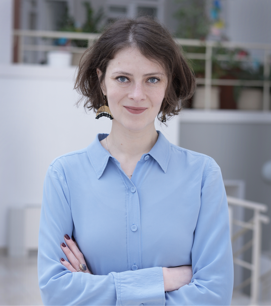 A young woman in a blue shirt is looking straight into the camera