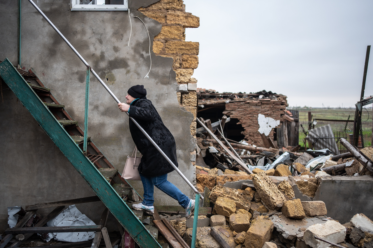 A woman climbs the stairs of a bombed-out building