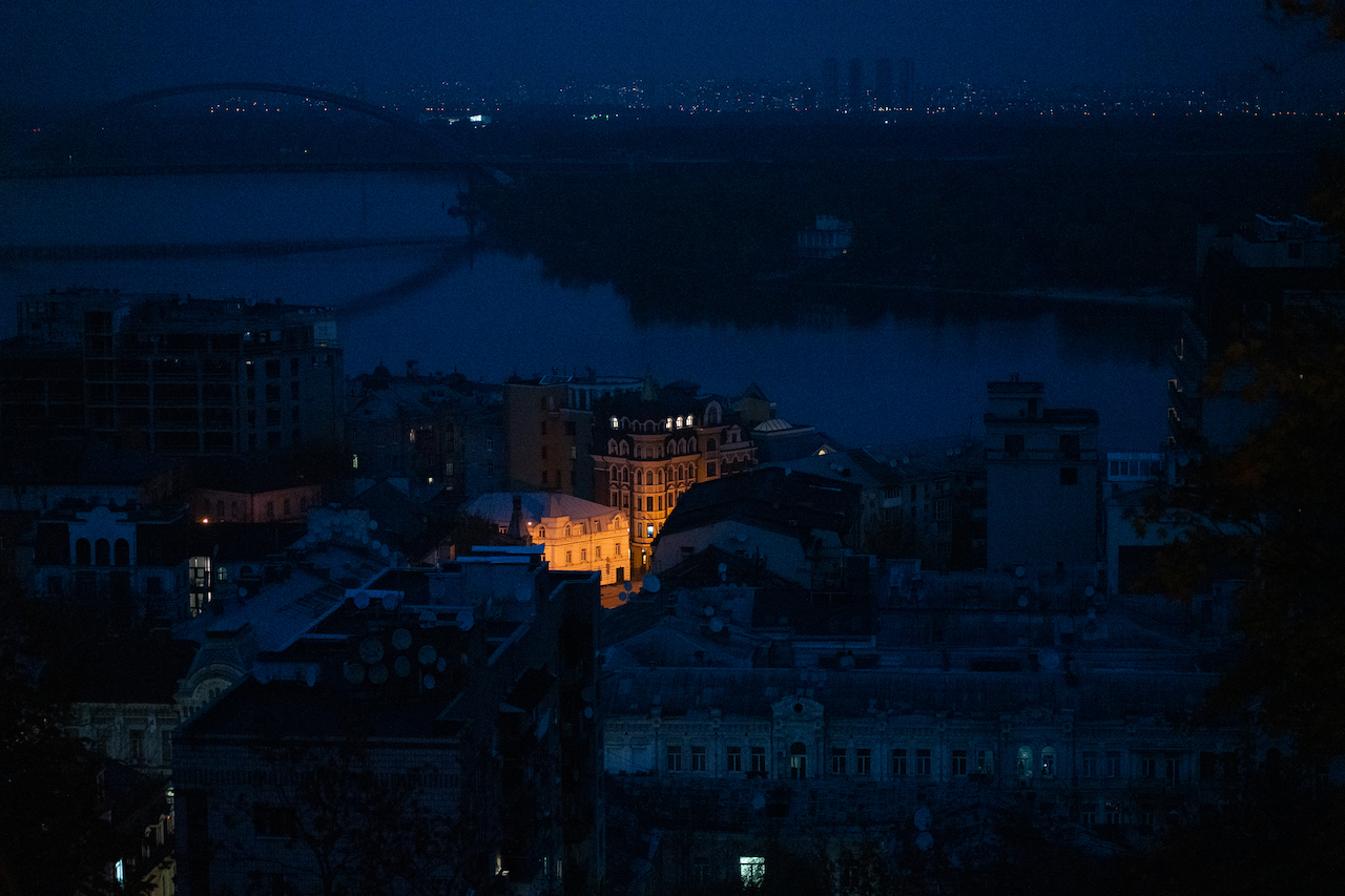 A completely dark city at night, with only a little light near one building