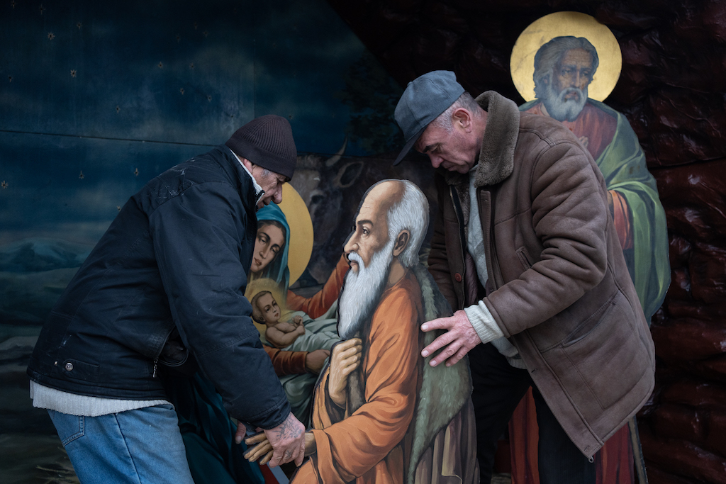 Two men carry a full-length image of the saint