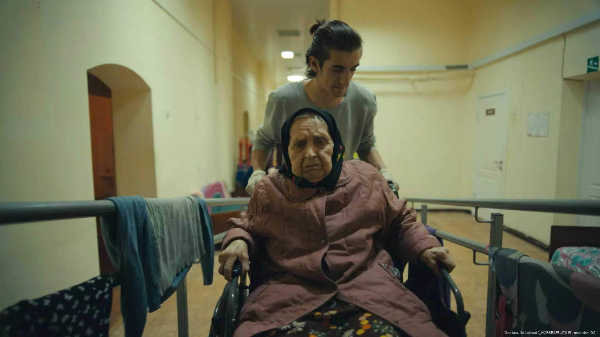 A volunteer helping an old lady in a wheelchair