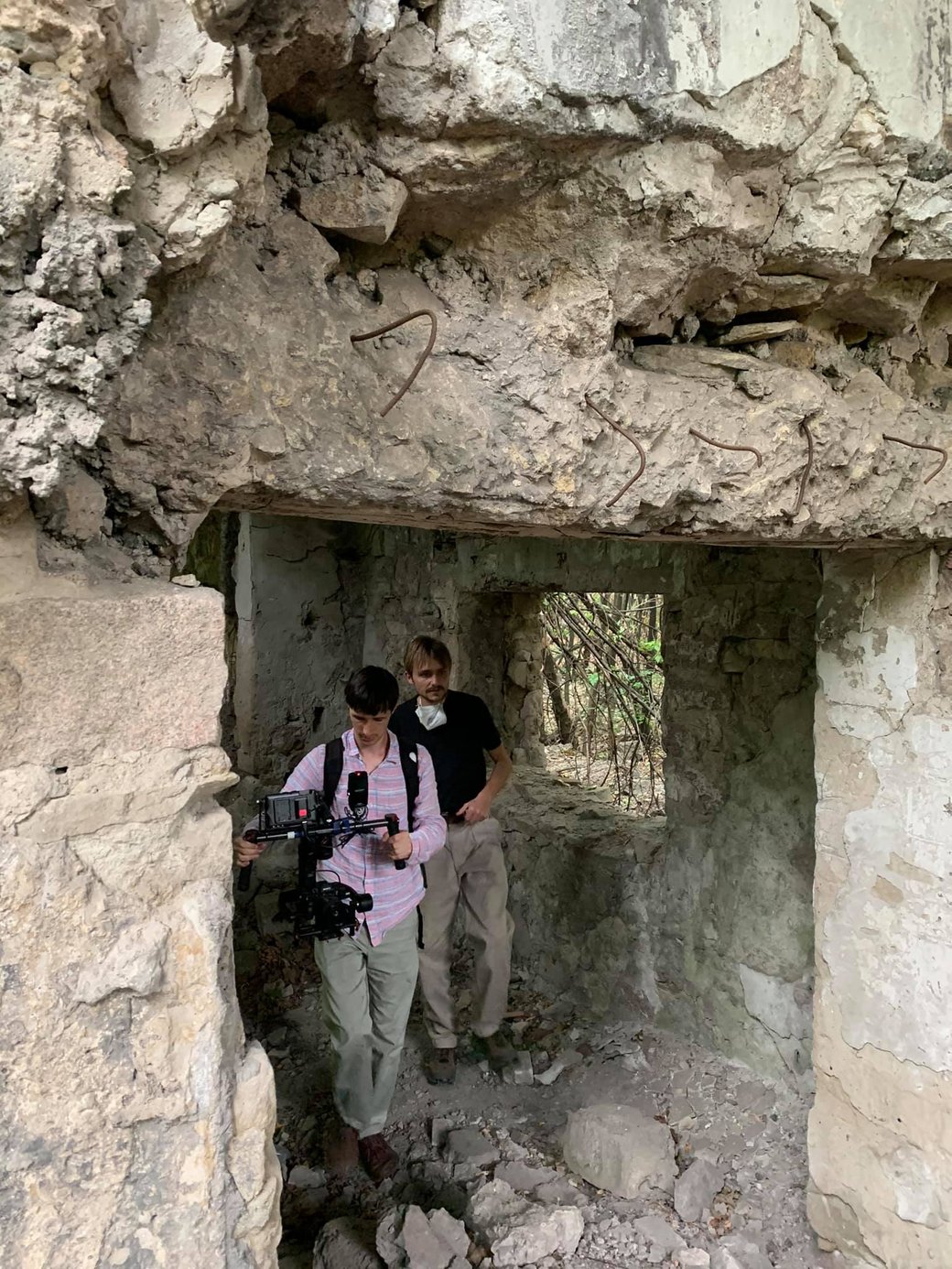 Two men with a camera in a ruined building