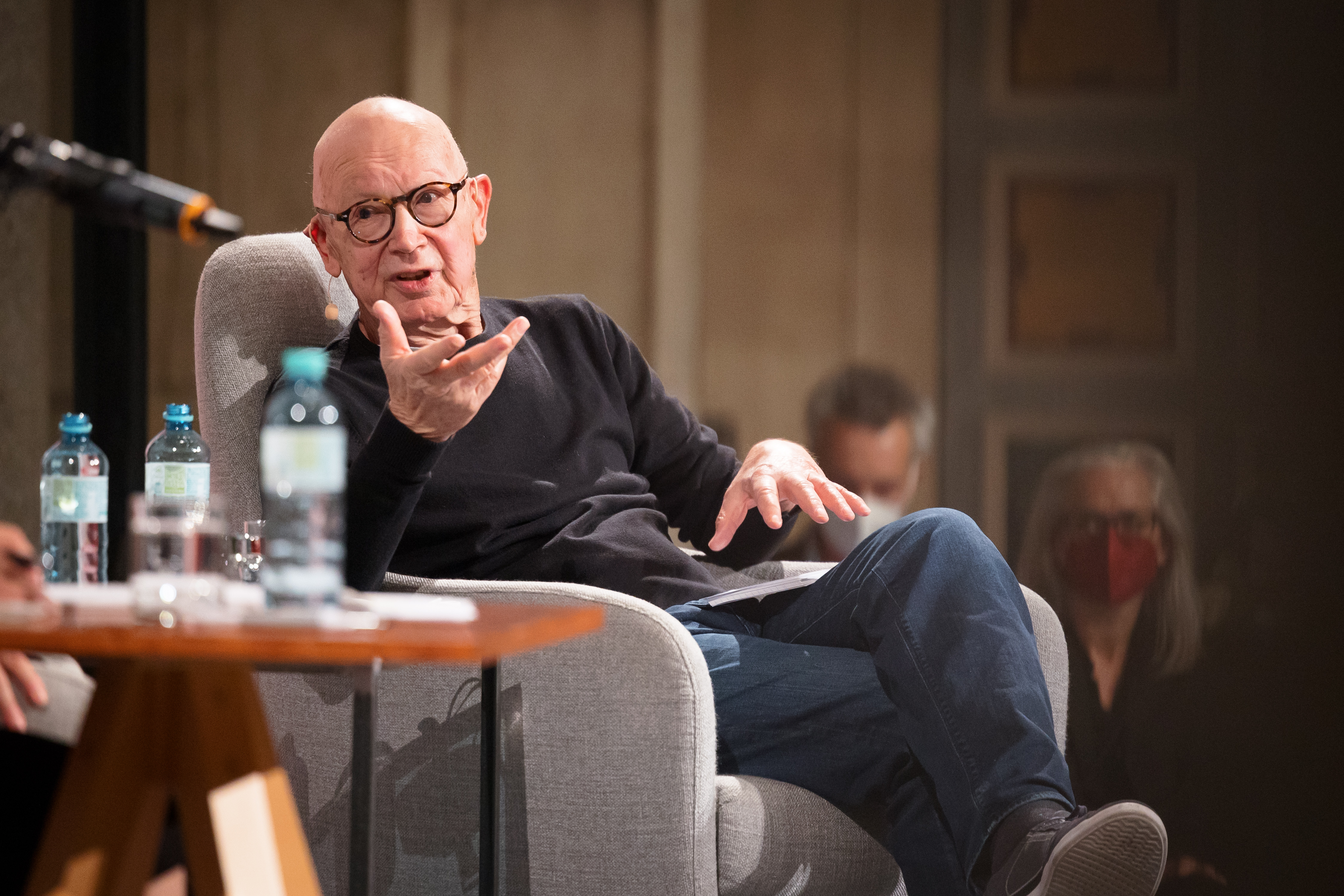 Martin Pollack seated in a grey armchair on the chair in discussion with Olga Tokarczuk