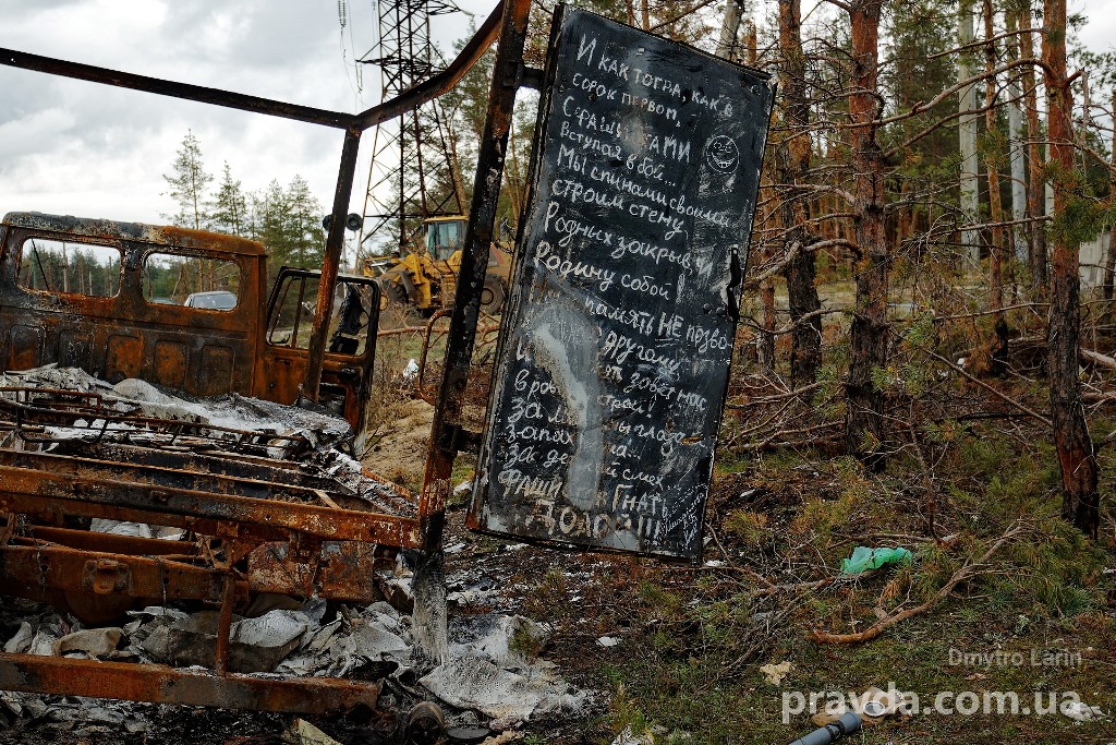 The remains of a burned car with an inscription on the door