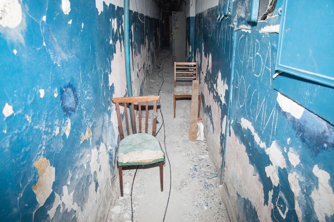 A corridor of the torture chamber with shabby blue walls and two chairs
