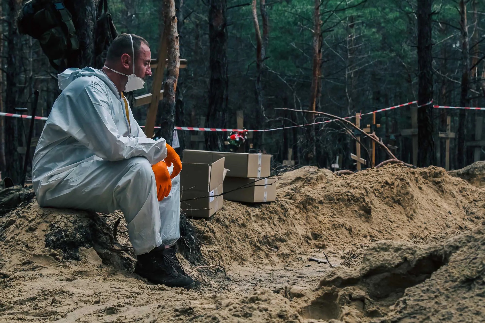 Man sits next to mass grave in Izium