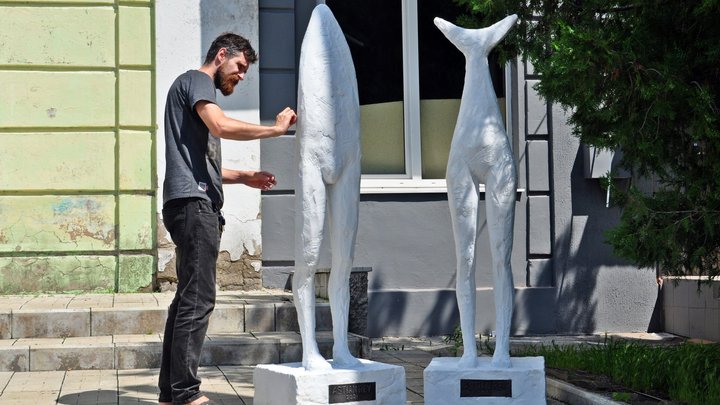 "A sculptor working on two sculptures"