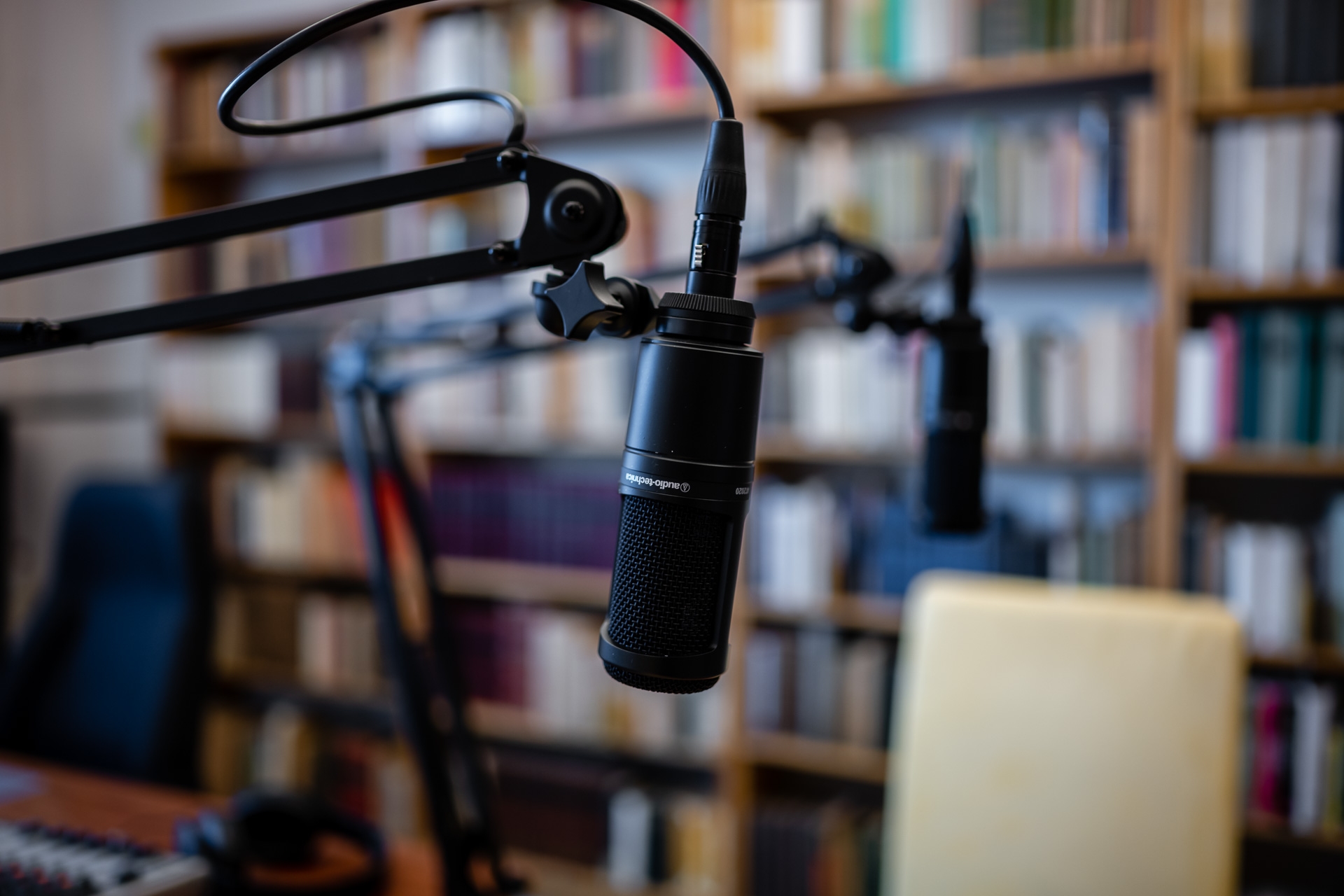 Two podcast recording microphones in front of a wall of books at the IWM. 