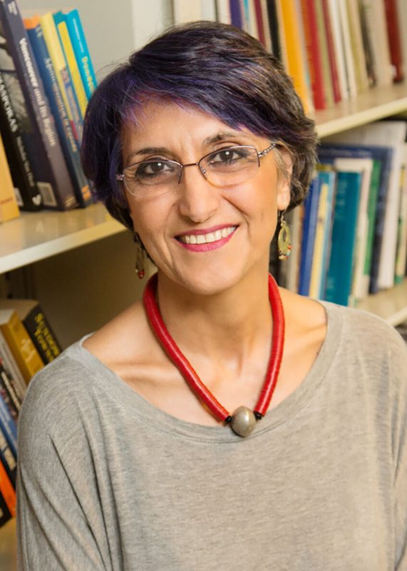 Faranak Miraftab in front of a bookshelf with colourful books behind