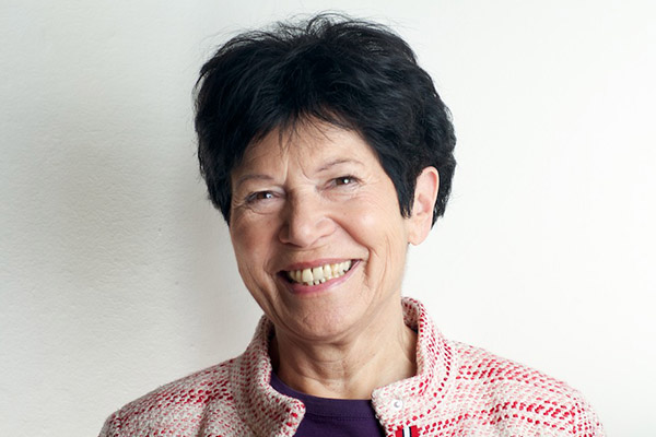 headshot of Helga nowotny, smiling into the camera, wearing a black top and a pink jacket