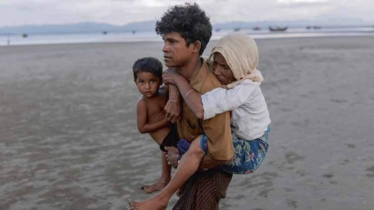 Rohingya-Flüchtlinge aus Myanmar in Bangladesch, Cox’s Bazar, 29. September 2017. Man walks with a child on his back and on his arm on the beach