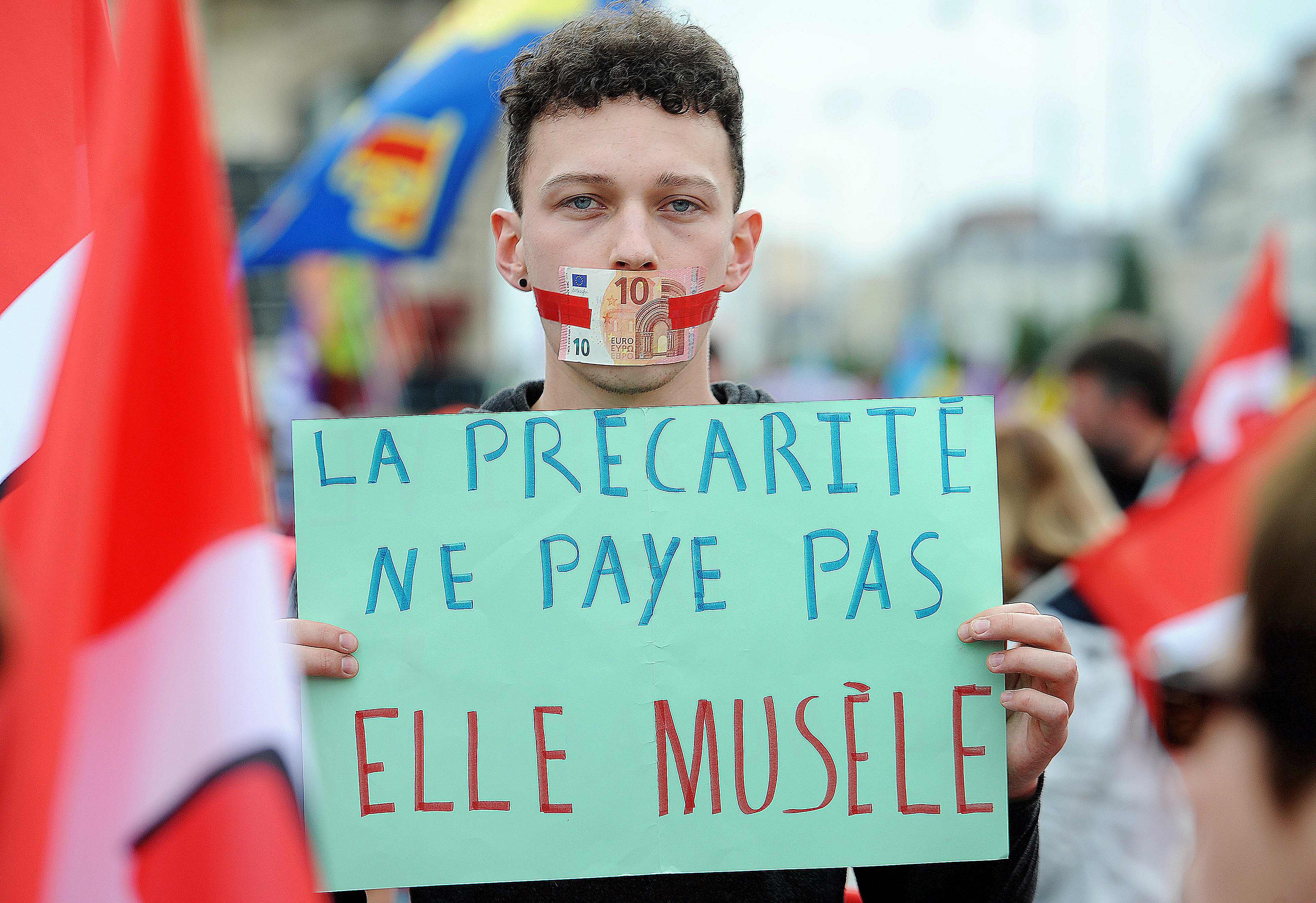 A man displays a placard which translates as ‘precarity doesn’t pay, it muzzles’ during a protest against controversial labor reforms on June 28, 2016 in Rennes.