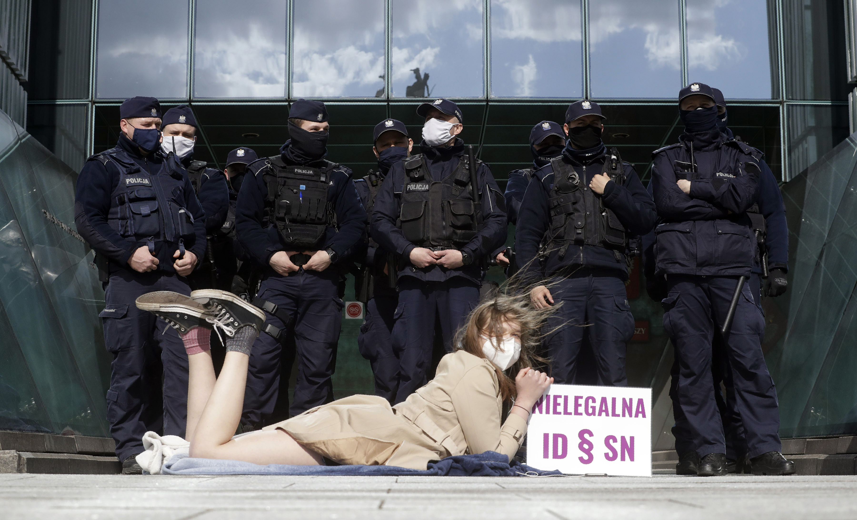 Policemen guard Poland’s Supreme Court as a protester lies on the pavement in Warsaw, Poland on Thursday, April 22, 2021. A disputed disciplinary body within Poland’s Supreme Court is examining amotion that could result in the arrest of a judge who has become a symbol of the fight for an independent judiciary.