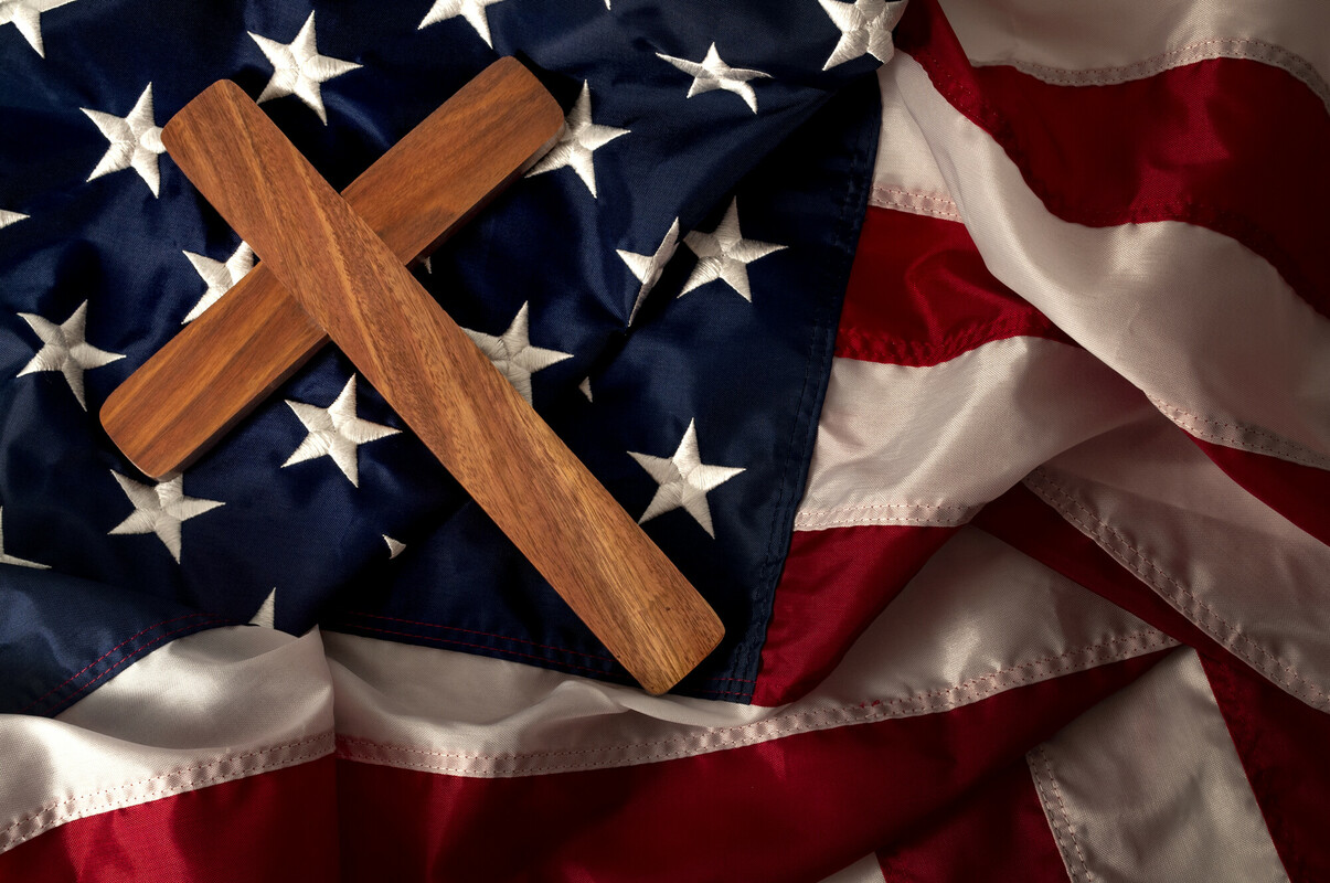 A picture of the flag of the United States with a Christian cross lying on it