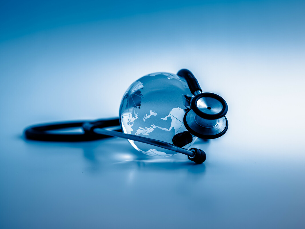 Stethoscope and a small globe in front of a blue background