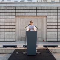 Oleksandra Matviichuk in a white dress stands on the podium