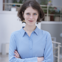 A young woman in a blue shirt is looking straight into the camera