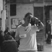 A woman stands with a camera depicting herself 