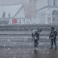 Two reporters standing in front of a "I Love Ukraine" sign