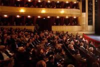 A photo looking from stage left out over a full audience at the Burgtheater with the house lights dimmed.